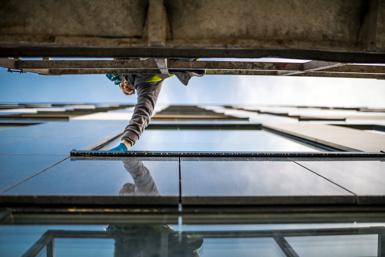 A window cleaner in action on a high-rise building, reflecting modern architecture.