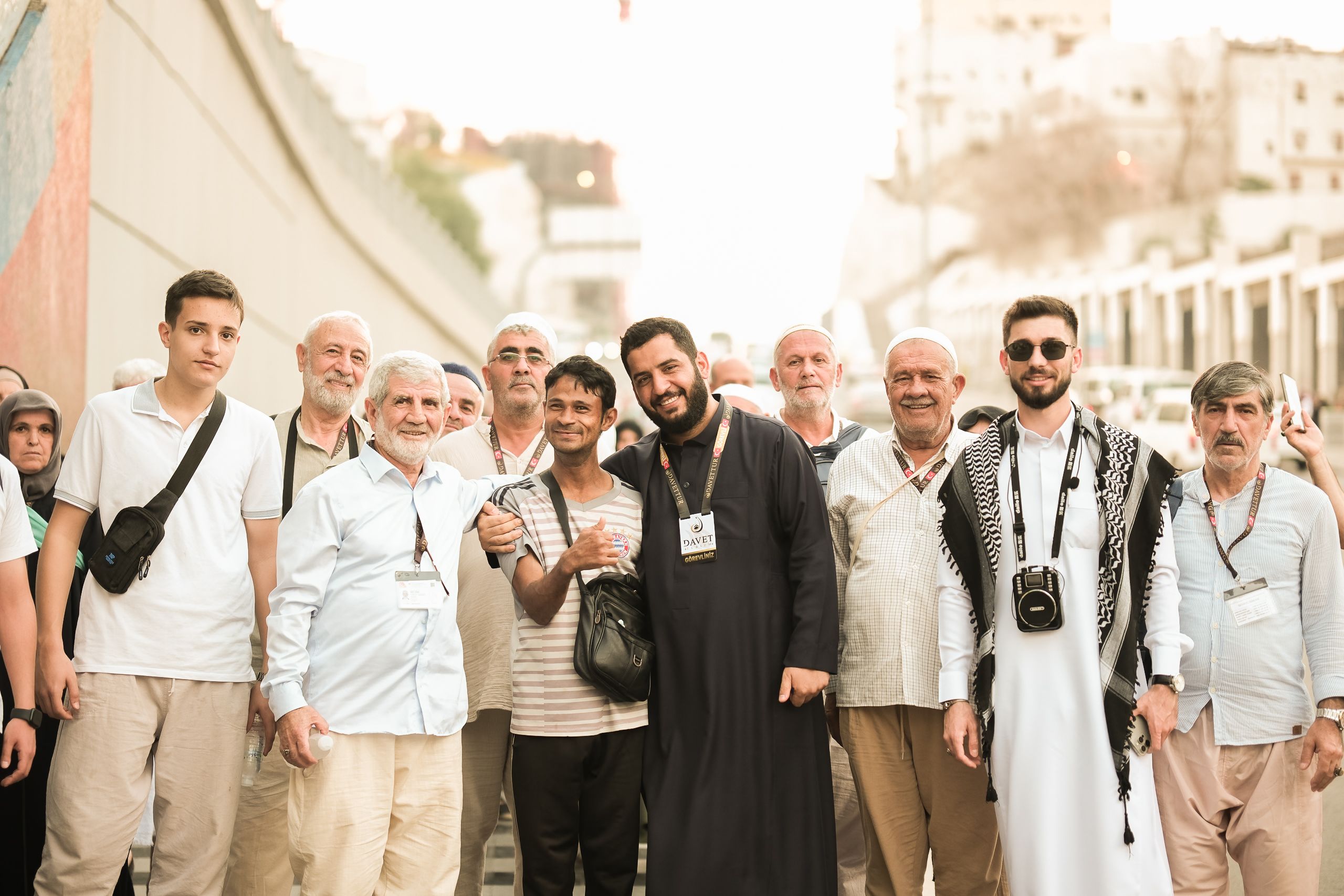 A group of adults gathered outdoors wearing traditional Middle Eastern clothing in Mecca, Saudi Arabia.